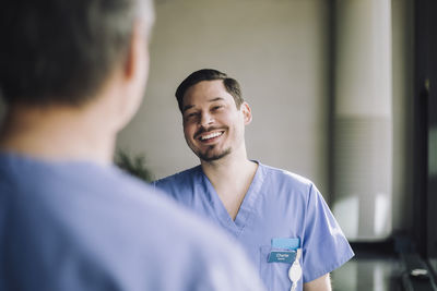 Smiling medical practitioner talking with senior male colleague at hospital