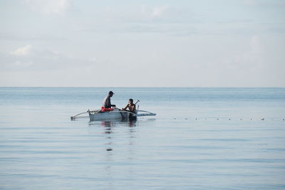 Man kayaking on sea against sky