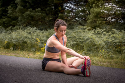 Portrait of woman sitting on road against trees