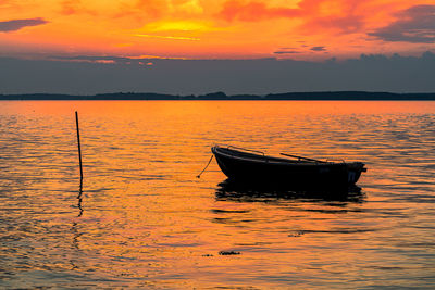 Boat moored on sea against sky during sunset