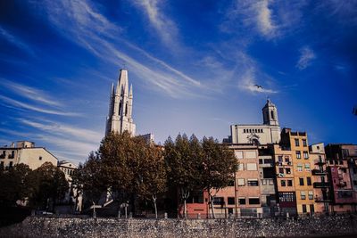 Tower amidst trees and buildings against sky