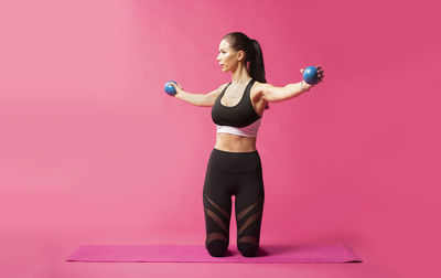 Full length of woman standing against pink background