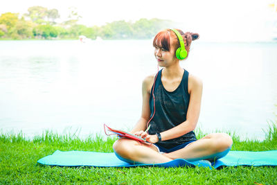 Young woman sitting by lake