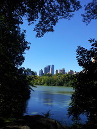 Buildings by river against clear sky