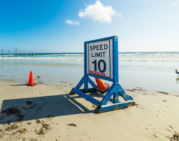 Information sign on beach against sky