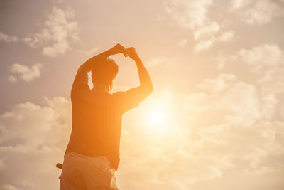 Midsection of woman standing against sky during sunset