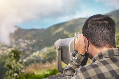 Tourist using binoculars looking at the city caracas from an observation point in the avila.