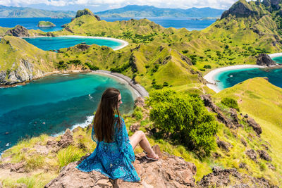 Rear view of woman sitting on mountain