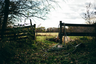 Abandoned swing on field against sky