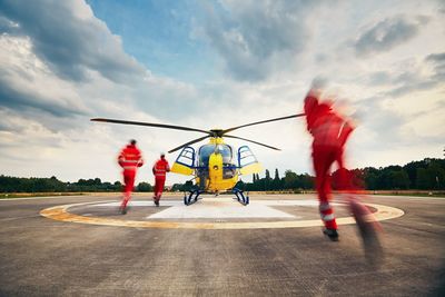 Rear view of paramedics running towards helicopter