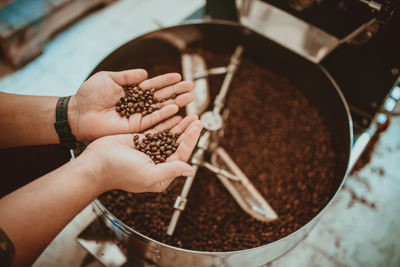 Cropped hands of man holding coffee beans while standing in shop