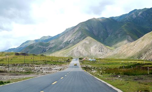 Road leading towards mountains against sky