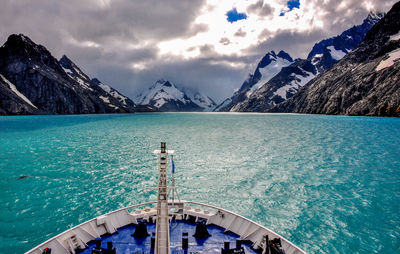 Scenic view of sea by snowcapped mountains against sky