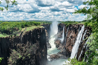 Scenic view of waterfall in forest against sky