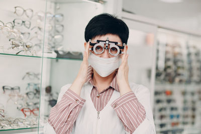 Portrait of woman holding optometry equipment at store