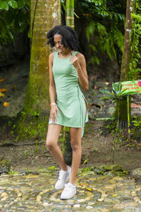 Full length of young woman standing in forest