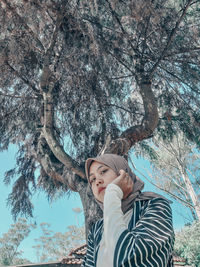 Portrait of woman sitting by tree trunk