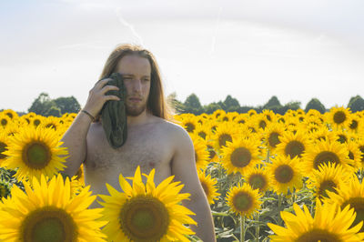 Close-up of woman standing on sunflower field against sky