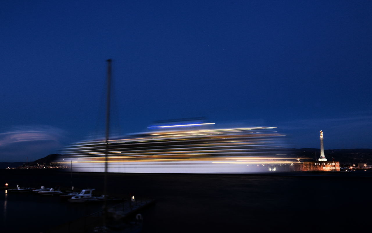 LIGHT TRAILS ON CITY AGAINST CLEAR BLUE SKY