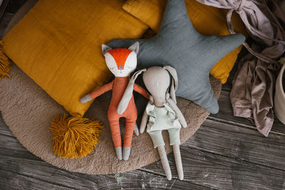 Homemade stuffed toys lie next to brightly colored pillows