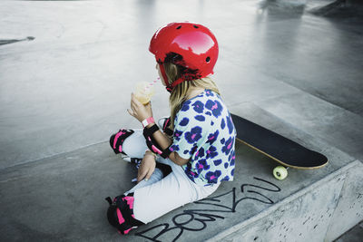 High angle view of girl drinking juice while sitting at skateboard park