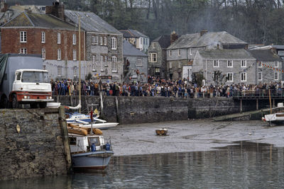 People by river and buildings in town