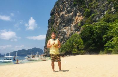 Young man standing on beach against sky