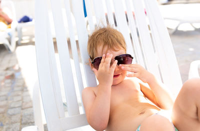 Small child in panama hat plays in the summer on sunny day near swimming pool