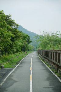 Road amidst trees against clear sky