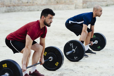 Two weightlifters lifting weights in an urban environment.