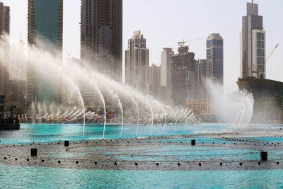 View of fountain by swimming pool against buildings in city