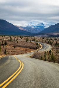 Road leading towards mountains against sky