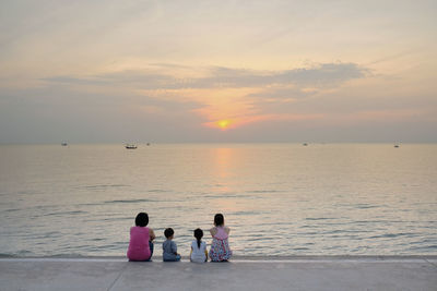 People on sea against sky during sunset