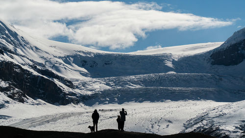 People on snowcapped mountain against sky