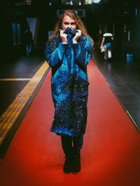 Young woman photographing with mobile phone while standing in bus