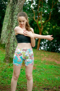 Beautiful young woman exercising against trees