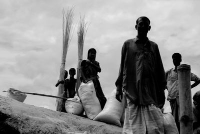 People with broom standing against sky