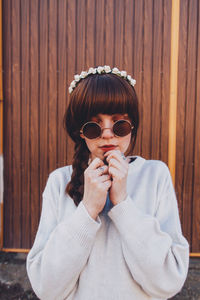 Woman wearing sunglasses while standing against wall