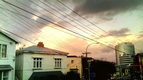 Low angle view of power lines against cloudy sky