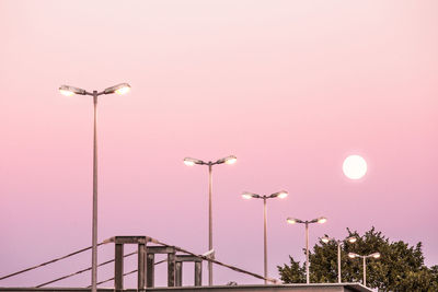 Low angle view of illuminated street lights against clear sky at dusk