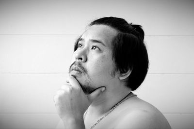 Close-up of man looking up while sitting against wall