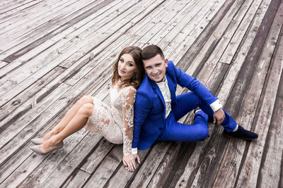 Happy friends sitting on wooden floor