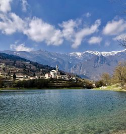 Scenic view of buildings by mountains against sky