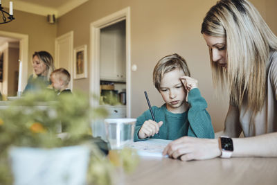 Blond woman assisting son with homework at home