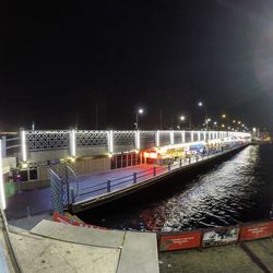 Boats moored in river against illuminated city at night