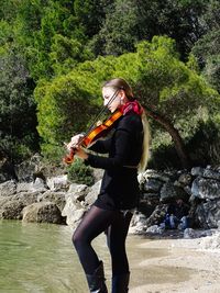 Young woman playing violin at beach