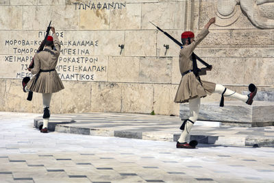 People walking on street against wall in city