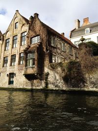 Old building by river against sky