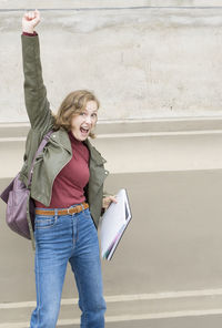 Young student girl jumps and gesticulates expressing joy about passing the exam