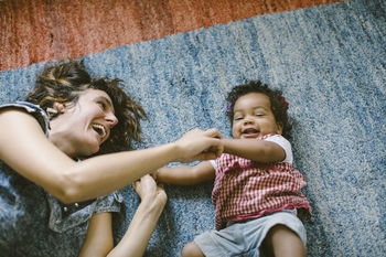 High angle view of happy mother and daughter lying on carpet at home